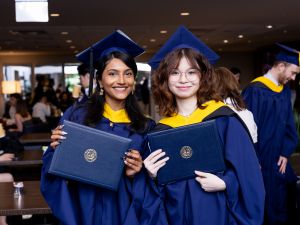 2 students smiling at the camera during graduation
