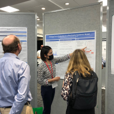 Professors Herring and Banks watch Jenny Huang explain a graphic detail on a research poster at ISBA 2022 conference in Montreal. 